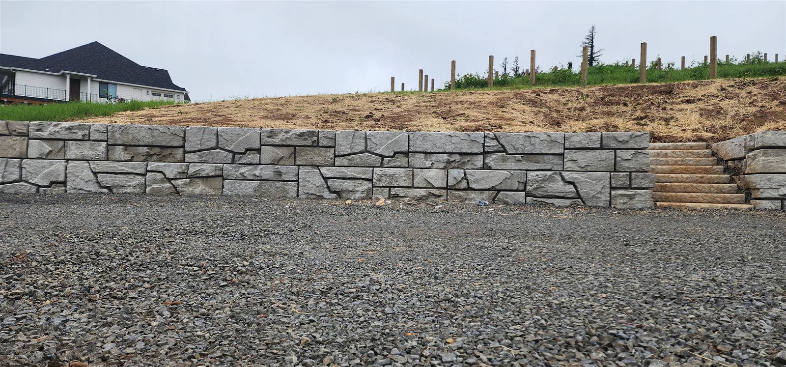Verti-Block wall with stairs beside a gravel pad below new homes