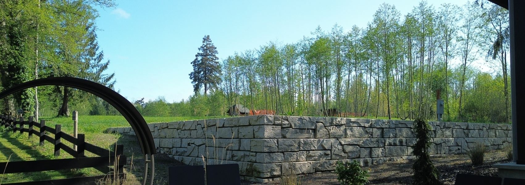 Verti-Block wall framing a meadow beside a fence and garden arch
