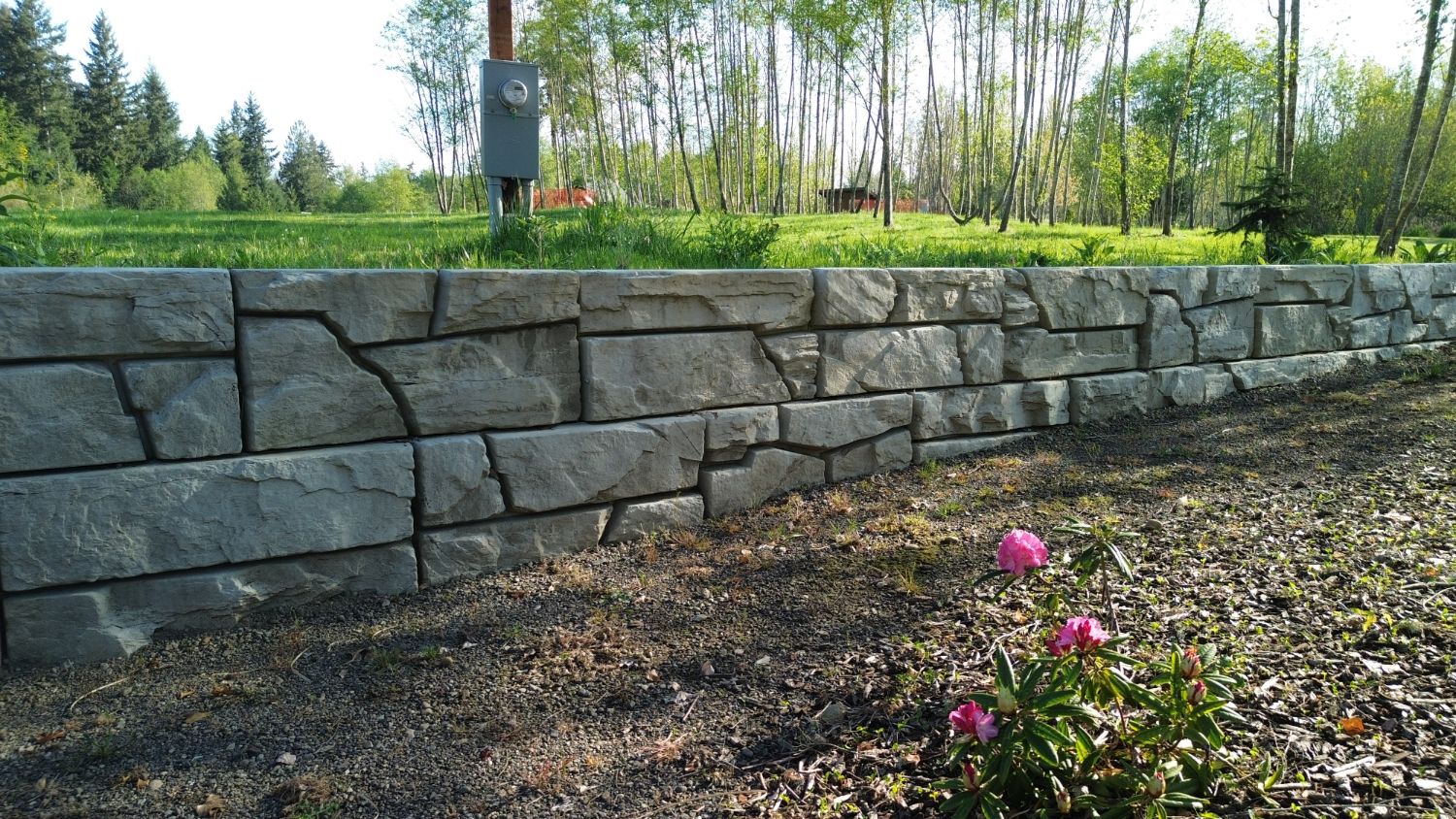 Verti-Block retaining wall with a natural stone face along a meadow